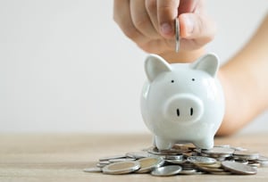 adding-coins-to-a-white-piggy-bank