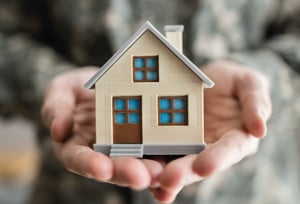 a person in military uniform holding a toy house